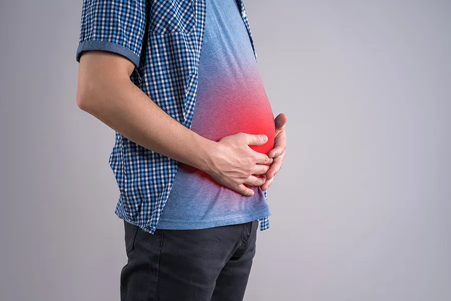 A man with a bloated belly. Get treatment for bloating from Tasmin Cordie, D.C. of Sage Functional Medicine in Marlboro Township.