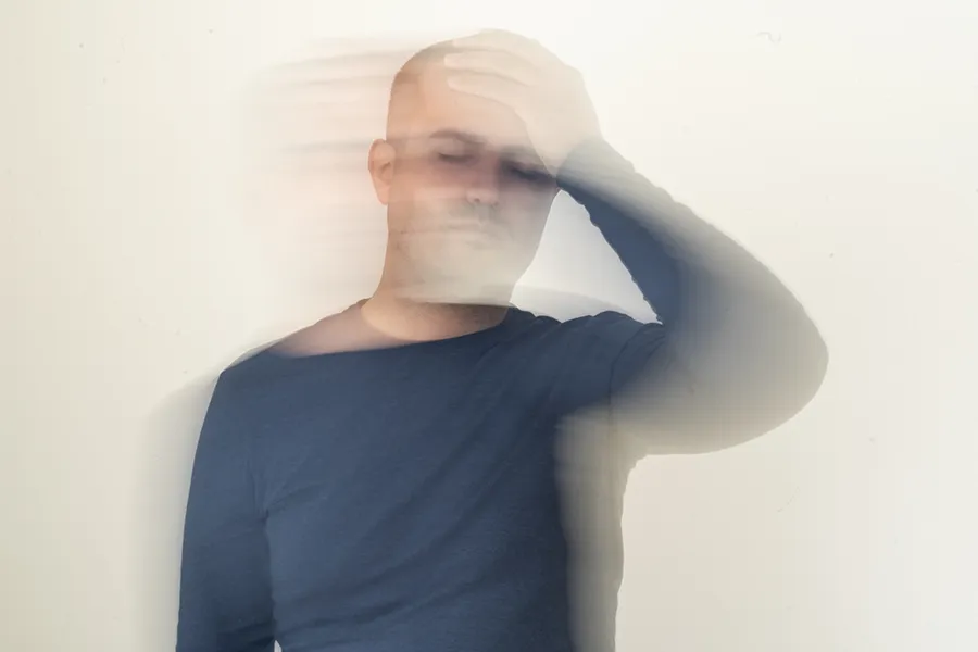 A motion-blurred image of a man holding his head. Get treatment for dizziness from Tasmin Cordie, D.C. of Sage Functional Medicine in Marlboro Township.