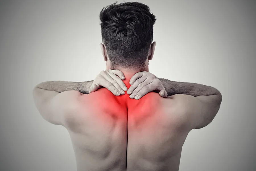 An image from behind of a man suffering from Fibromyalgia rubbing an area illustrated red with pain in his shoulders and neck . Get fibromyalgia treatment from Tasmin Cordie, D.C. of Sage Functional Medicine in Marlboro Township.