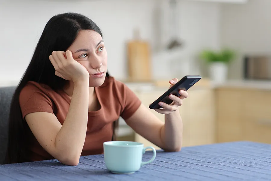 Focus-Issues-Clinic A woman stares into space with her phone in hand. Get treatment for focus issues from Tasmin Cordie, D.C. of Sage Functional Medicine in Marlboro Township.