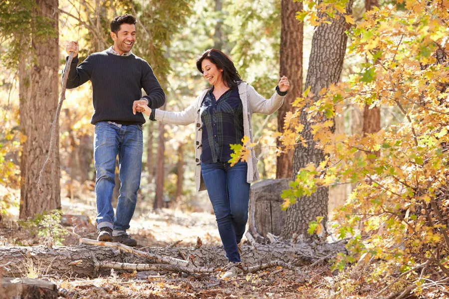A couple happily hiking in the forest in fall. Get treatment for Lyme Disease from Tasmin Cordie, D.C. of Sage Functional Medicine in Marlboro Township.