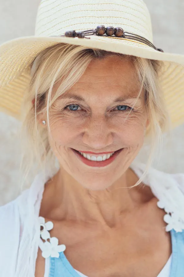 A beautiful, smiling older woman with blonde hair and a sunhat, happy with menopause treatment from Tasmin Cordie, D.C. of Sage Functional Medicine in Marlboro Township.