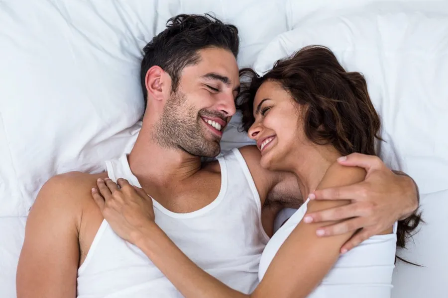 Sexual-Dysfunction-Clinic A couple laying in bed smile at each other. Schedule treatment for sexual dysfunction from Tasmin Cordie, D.C. of Sage Functional Medicine in Marlboro Township.