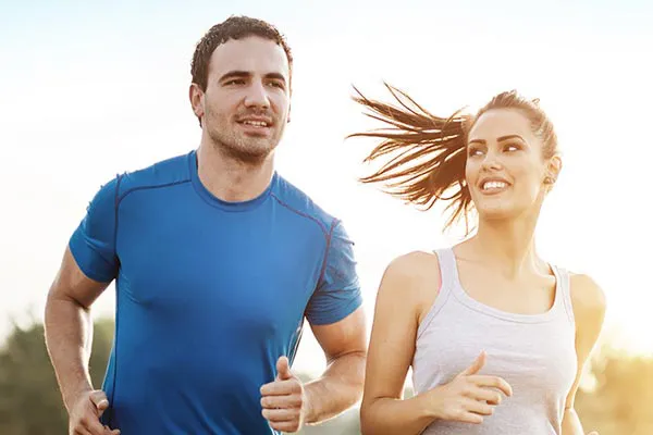 A couple happily jogging in the sunlight after receiving effective weight loss resistance care from Tasmin Cordie, D.C. of Sage Functional Medicine in Marlboro Township.
